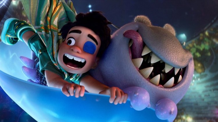 The main character Elio stands on a colorful alien planet beside his friend Glordon, a tall, eyeless alien, as they both look up in awe in a scene from Pixar's Elio.