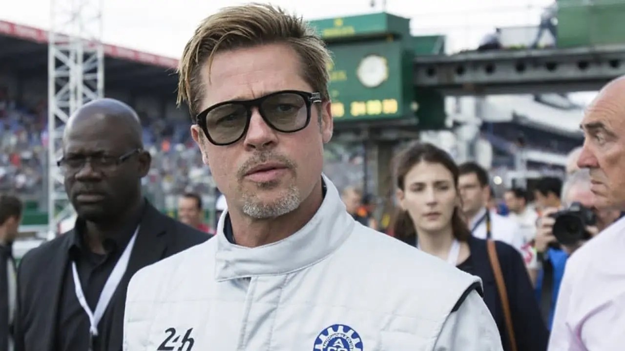 Brad Pitt in a white racing suit on set for the Apple Studios F1 movie, a key part of their strategy to become a major movie studio.