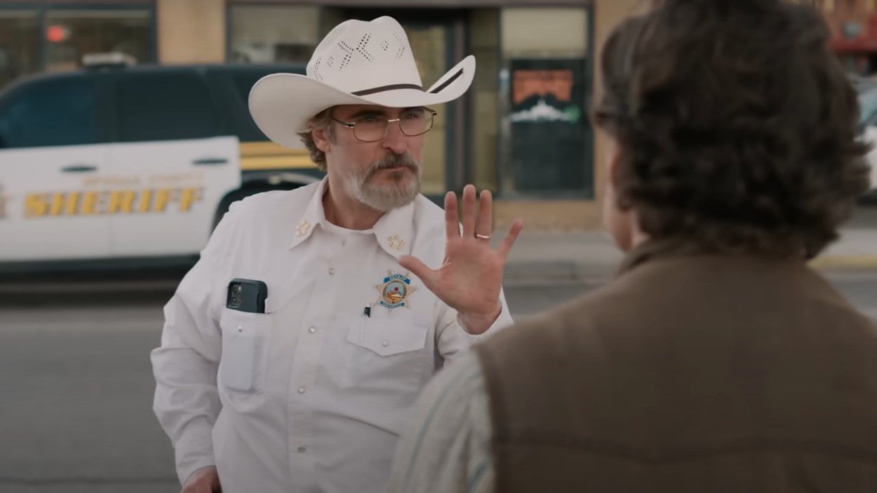 Sheriff Cross holds up his hand mid-conversation in Ari Aster's Eddington, set in a quiet Western town.
