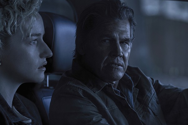 Julia Garner and Josh Brolin look on with concern in a tense, dark scene from the horror movie Weapons.